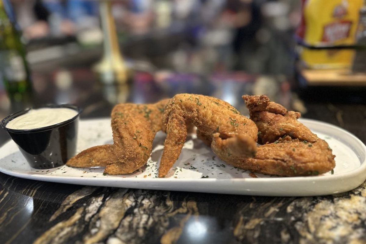The Three Legged Goat: Plate of fried chicken wings with dipping sauce on the bar