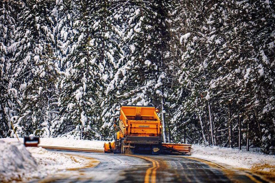 A snowplow clearing a two-lane highway in a northern state