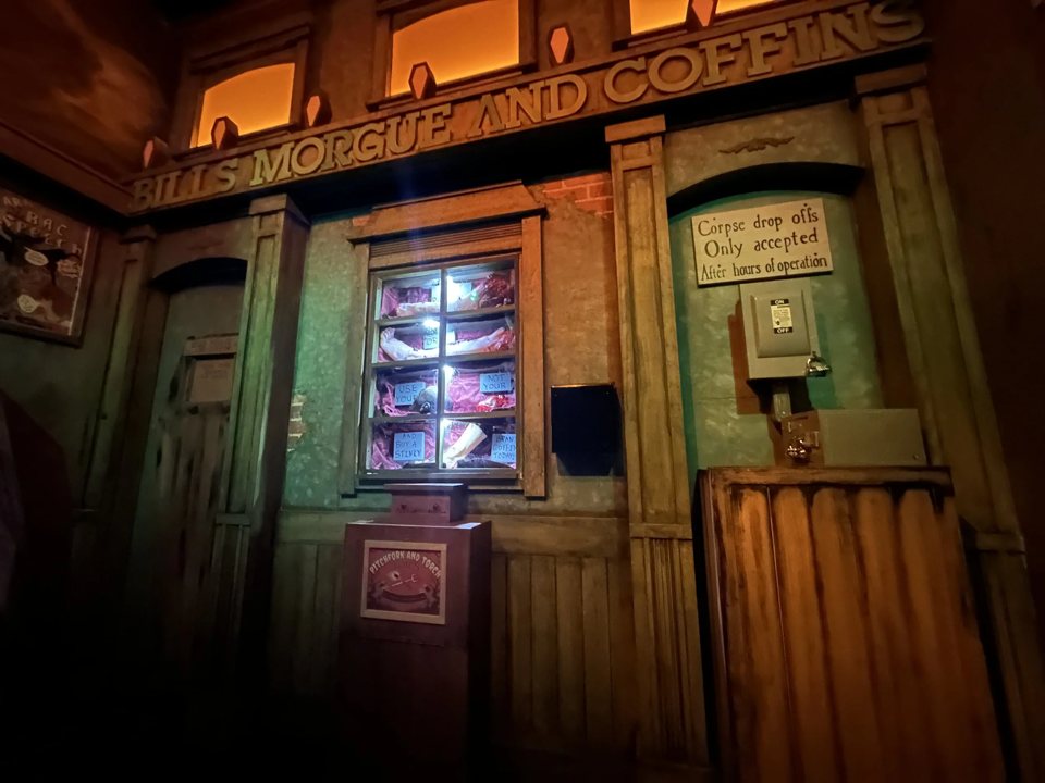 Old western-style storefront signed Bill's Morgue and Coffins with a lit display window