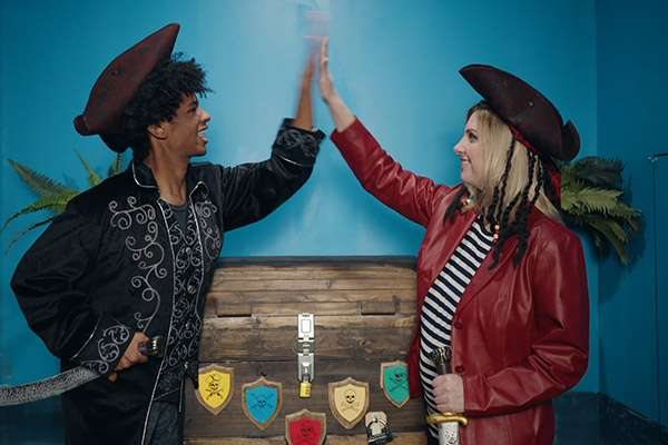 Two players in pirate costumes high-five by the wall of the pirate room