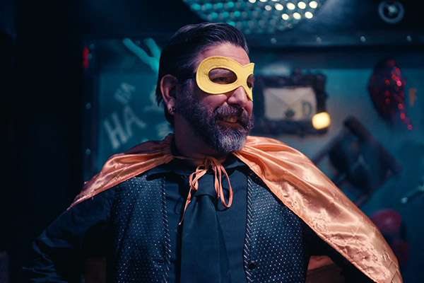 Costumed character in a gold mask and cape in the villain lair set
