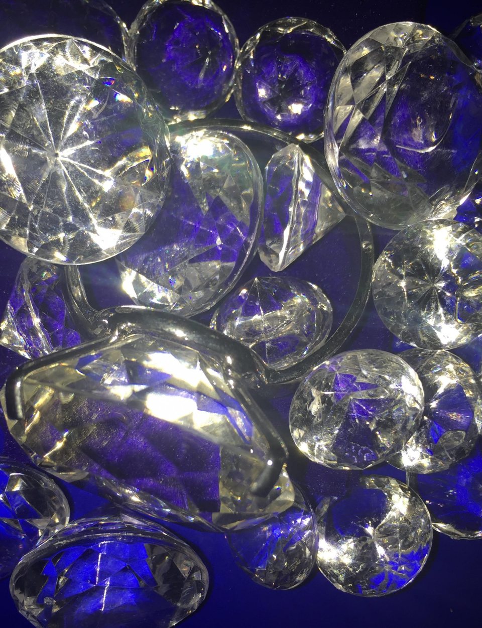A pile of sparkling fake gems under blue light