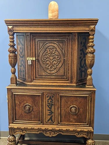 Carved antique cabinet with a padlock and a salt lamp on top