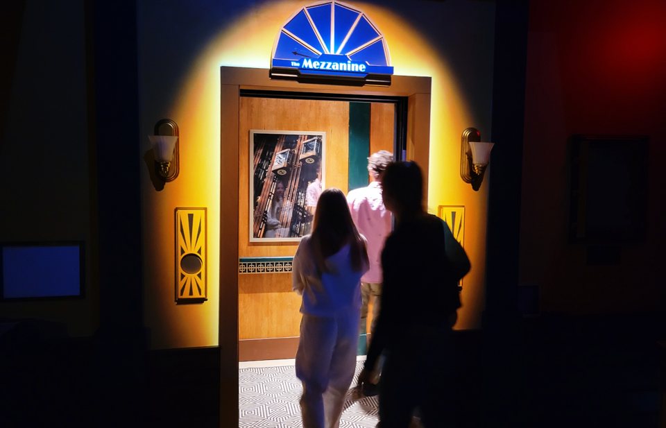 Players step through the lit Mezzanine doorway with its fan-shaped sign