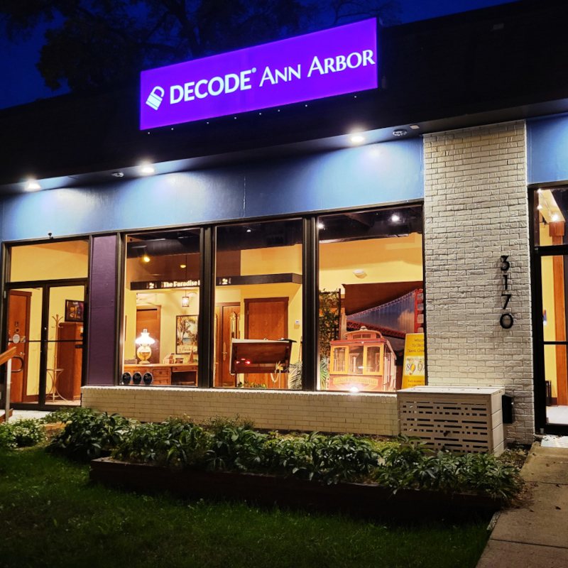 The lit storefront at dusk with the purple Decode Ann Arbor sign