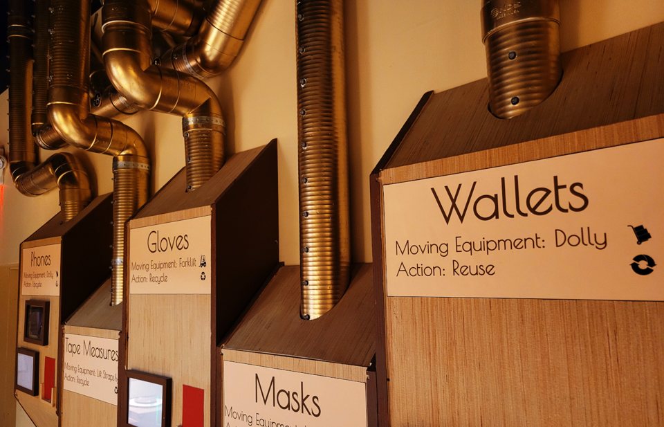 Labeled sorting bins fed by brass pipes along the wall