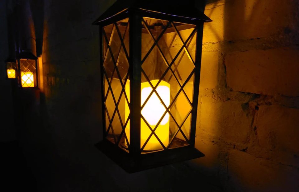 Candle lanterns glowing on a dark stone wall