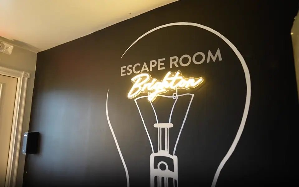 The lobby's black wall with a large light bulb drawing and a glowing Brighton neon sign