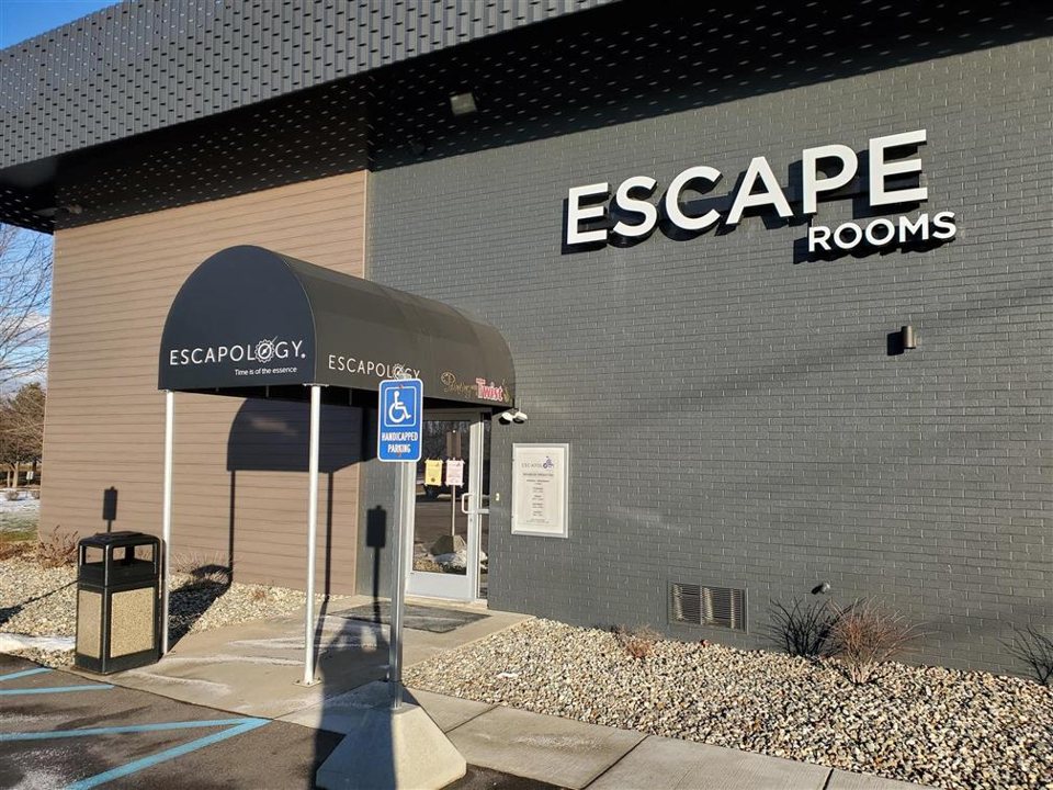 The Escapology building in Portage from outside, with the awning over the entrance and the Escape Rooms sign on the gray brick wall