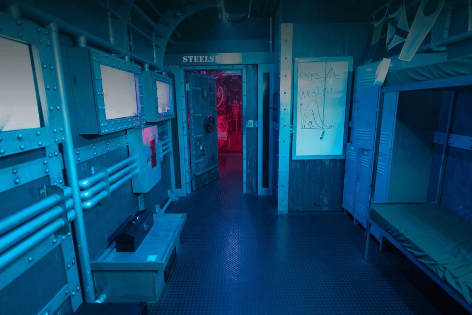 Submarine interior set with riveted steel walls, pipes, bunks and a red-lit hatch in the back