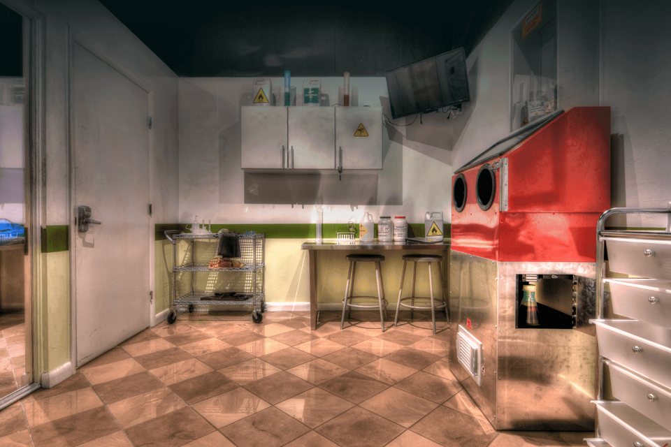 Laboratory set with hazard-labeled cabinets, chemical bottles and a red glovebox station