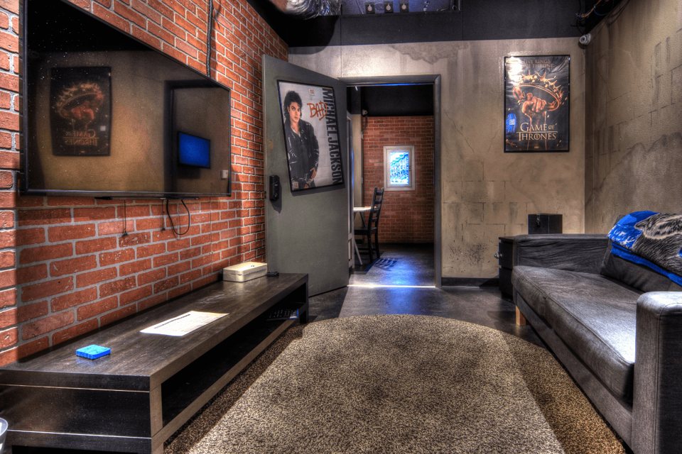 Loft-style room with a brick wall, a large TV, a leather sofa and movie posters on the walls