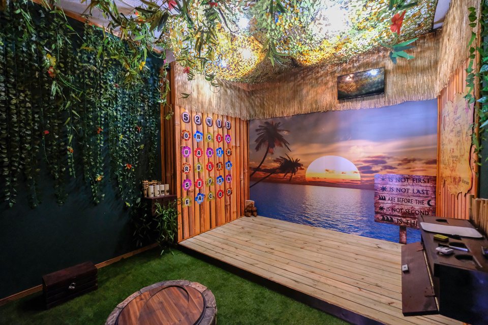 Tropical island room with a sunset beach mural, a wooden deck, jungle vines and a puzzle board of colored letters