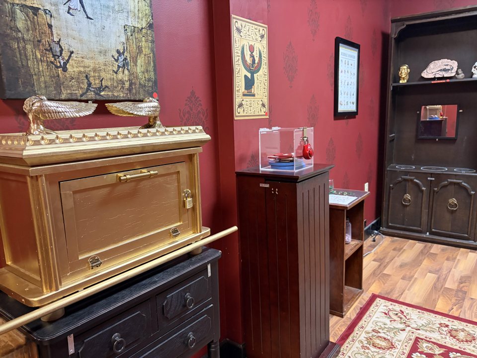Red damask room with a golden Ark of the Covenant replica, Egyptian artwork and a relic display case