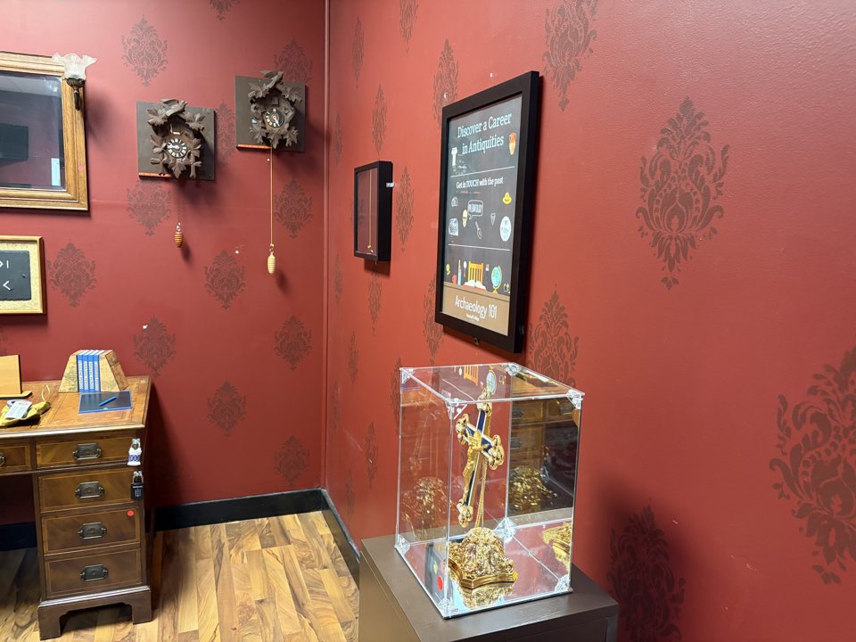 Archaeology-themed room with cuckoo clocks, an antique desk and a golden relic in a glass case