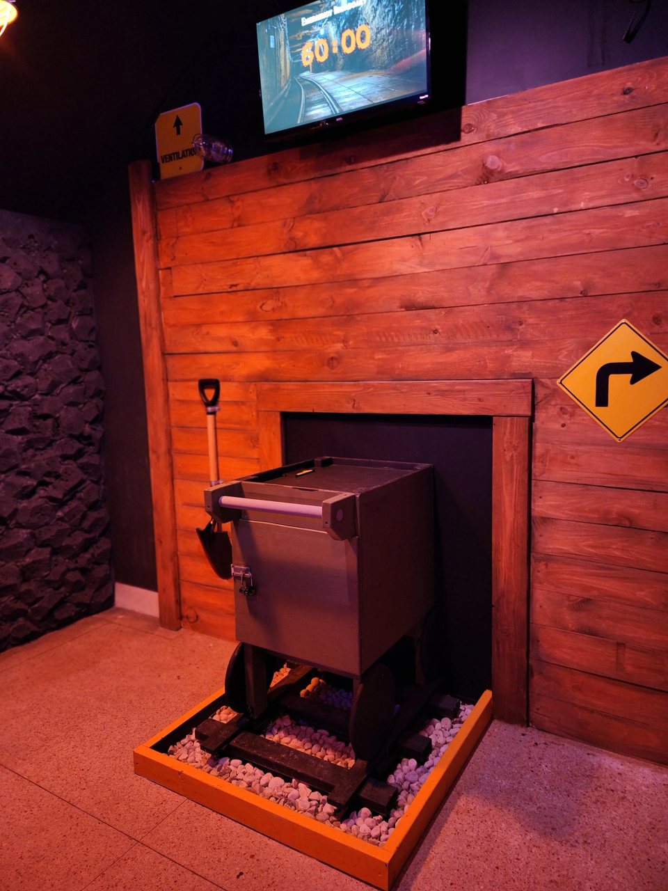 Ore cart on tracks in front of a wooden wall with a road sign and a countdown screen