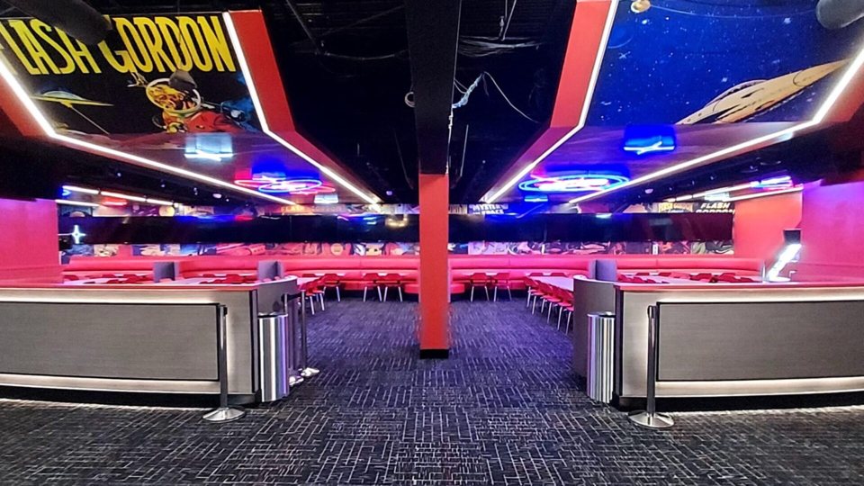 The entertainment center's neon-lit lounge with red booths, chairs and Flash Gordon comic murals