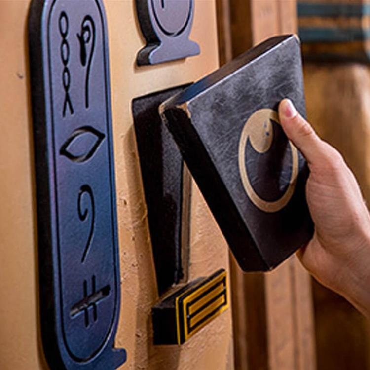 A hand fits a symbol block into the hieroglyph wall of the Egyptian-themed escape room