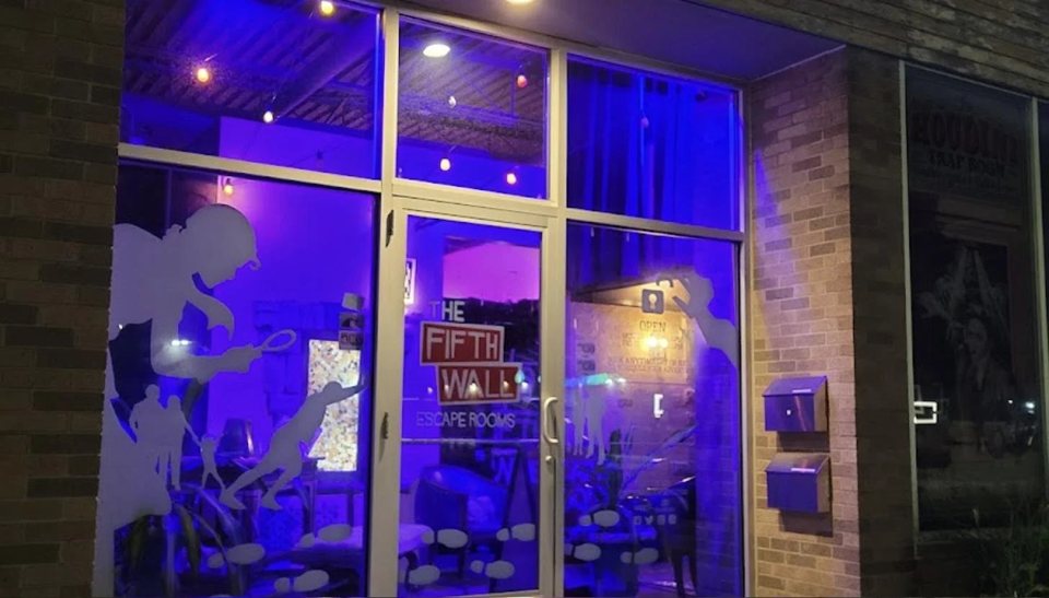 The Fifth Wall storefront at night, lit purple, with the logo and detective silhouettes on the glass