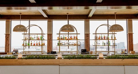 The bar at Topa with arched liquor shelves in front of windows overlooking the city