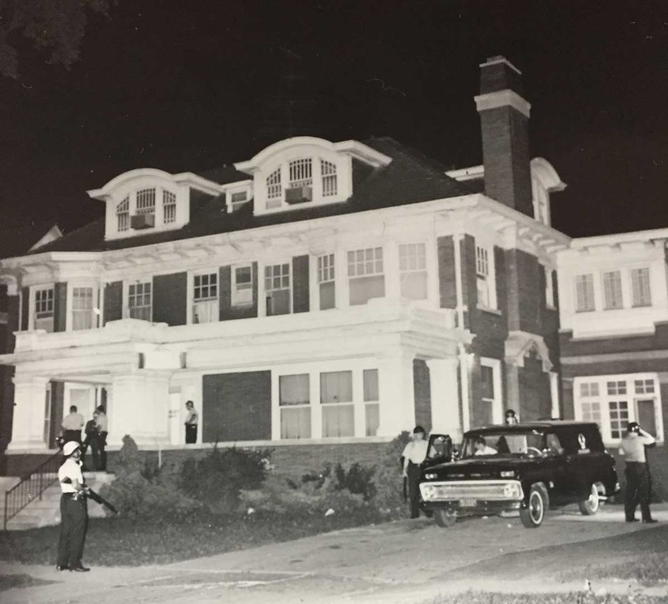 The Algiers Motel annex, a brick house with dormer windows, with police officers and a car out front on the night of July 26, 1967