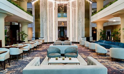 The multi-storey lobby with marble columns and blue sofas