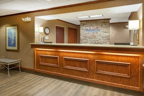 The front desk with a wooden counter and the Baymont sign on a stone wall