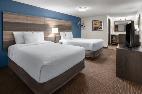 A guest room with two queen beds and a blue accent wall