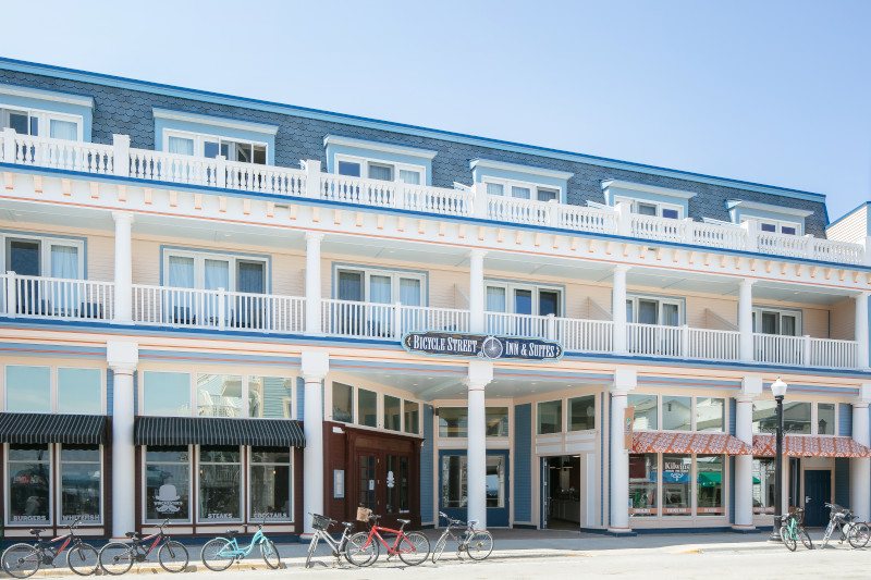 The hotel's white facade with balconies, the Bicycle Street Inn & Suites sign and bicycles parked out front