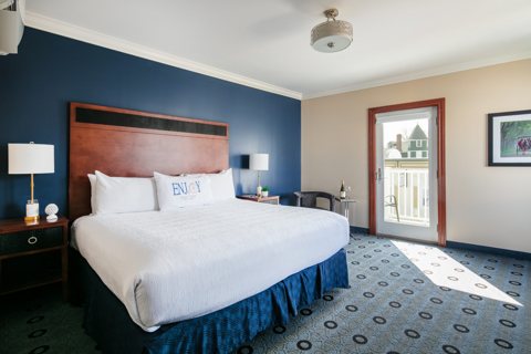 A guest room with a king bed, a navy accent wall and a balcony door