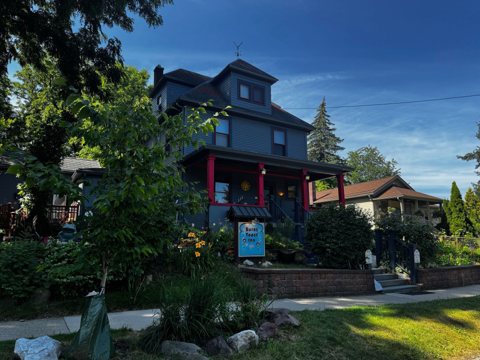 The inn's house with its garden and the sign seen from the sidewalk
