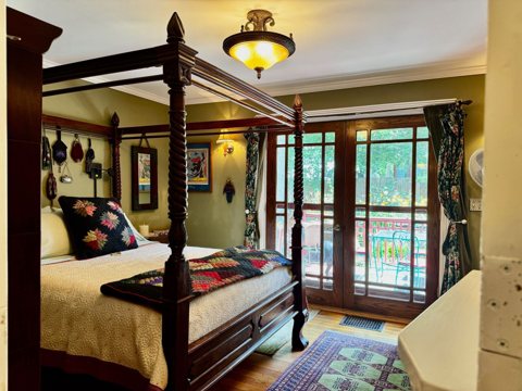 A guest room with a four-poster bed and glass doors opening to the garden
