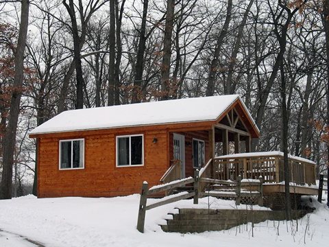 An orange wooden cabin in a snowy forest
