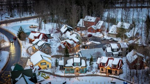 Colorful snow-covered cottages among the trees seen from above