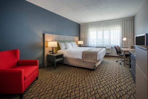A room with a large bed and a red armchair