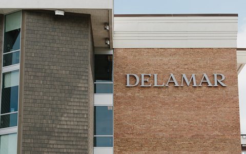 The hotel's brick facade with the DELAMAR lettering next to its shingle-clad wing