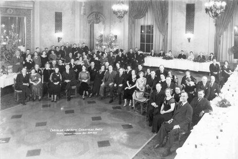 A black-and-white group photo of a December 1934 Christmas party in the hotel's chandeliered ballroom