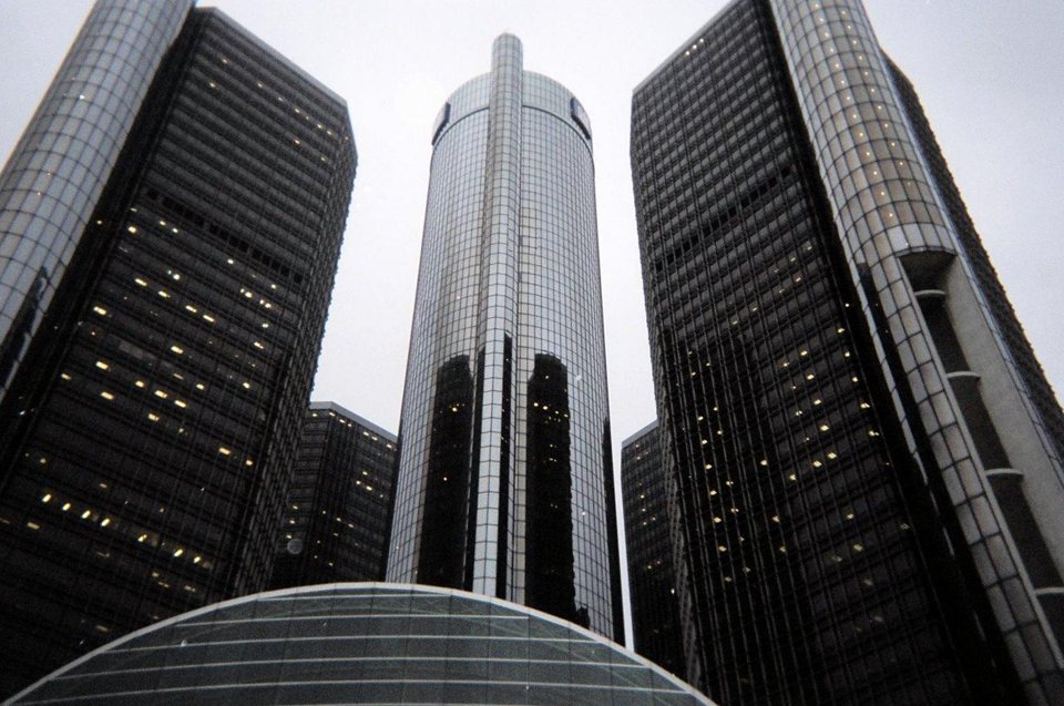 The Renaissance Center glass towers seen from below, with the hotel's cylindrical central tower in the middle
