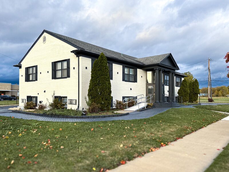 The white-painted two-storey brick DTW Suites building with a lawn