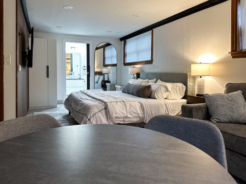 A bright guest room with a large bed and a table