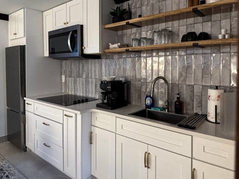 A kitchen with white cabinets and open shelving