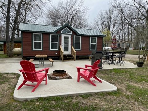 A small cabin with red chairs and a fire pit