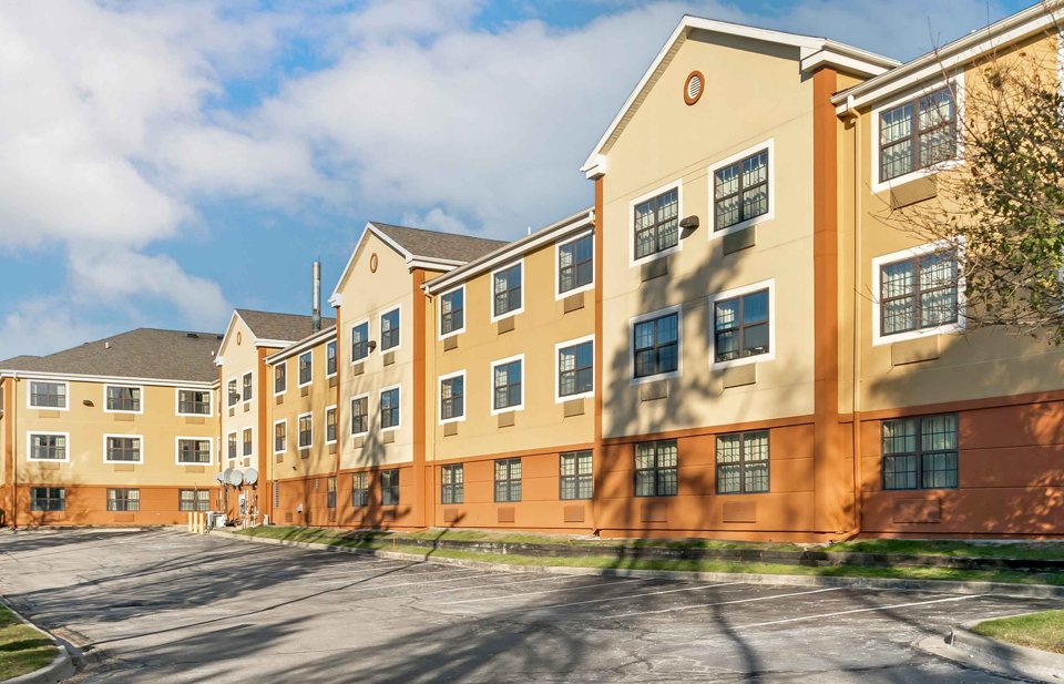 The hotel's yellow-facade building and parking lot in sunshine