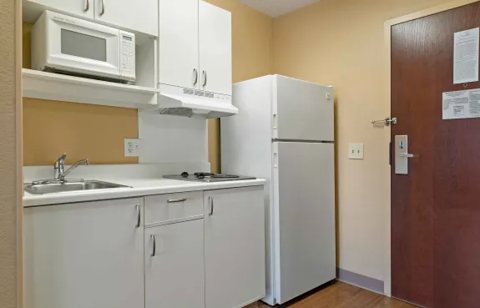 A kitchenette with a refrigerator and white cabinets