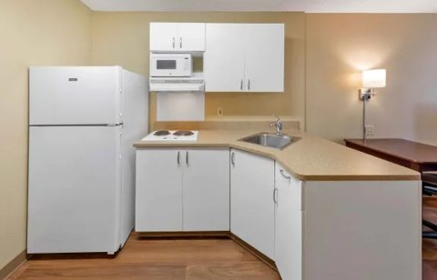 A kitchenette with a refrigerator and white cabinets