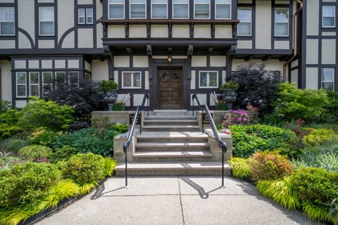The half-timbered front entrance with stone steps and a flower garden
