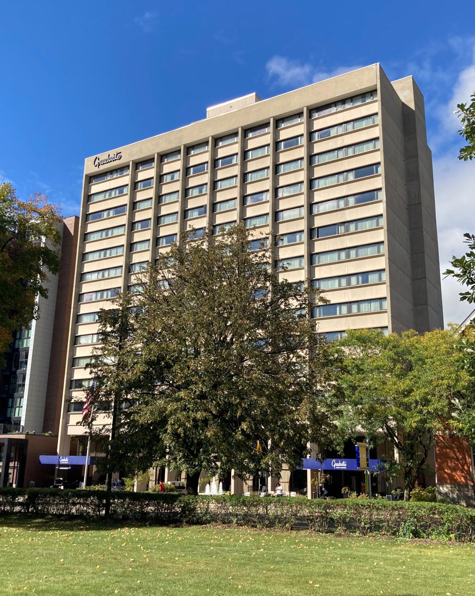 The Graduate hotel tower with the Graduate sign on its facade under a blue sky