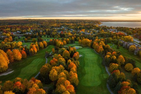 A resort golfpályája őszi fákkal felülről, háttérben az öböllel