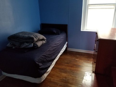 A blue-walled room with a bed and a window
