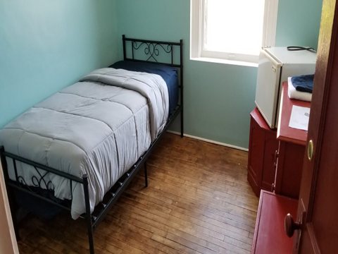 A light-blue room with single metal beds